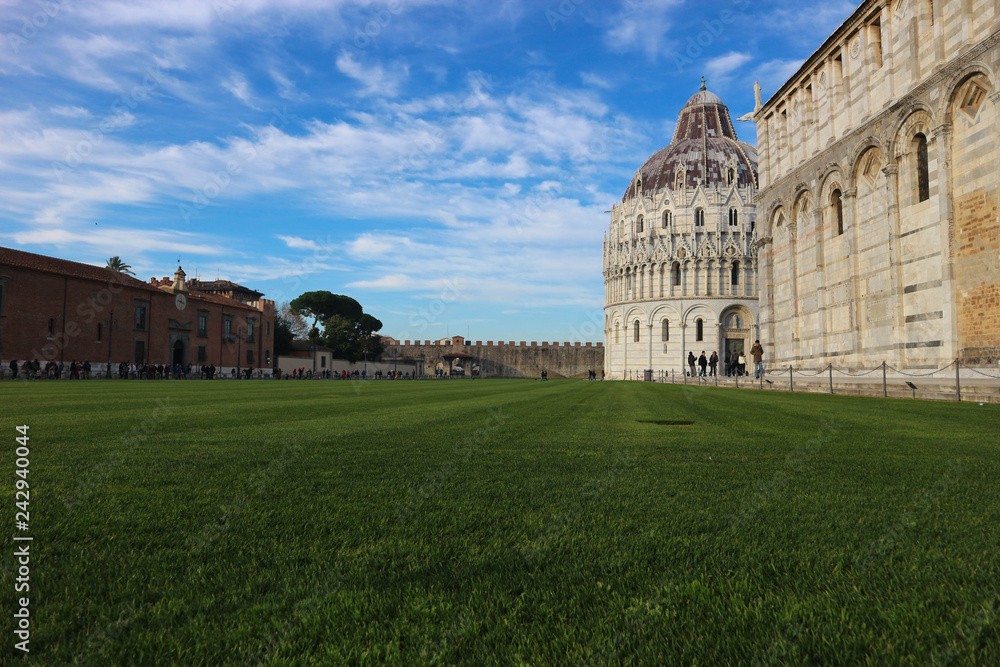 Green lawn at the piazza dei miracoli (square of miracles) with Pisa baptistery and cathedral, Tuscany, Italy