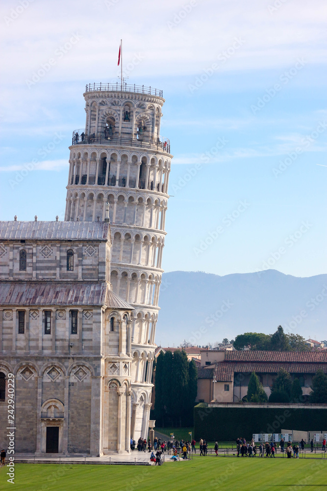 Leaning tower of Pisa, symbol of Italy, with Tuscany mountains on the background