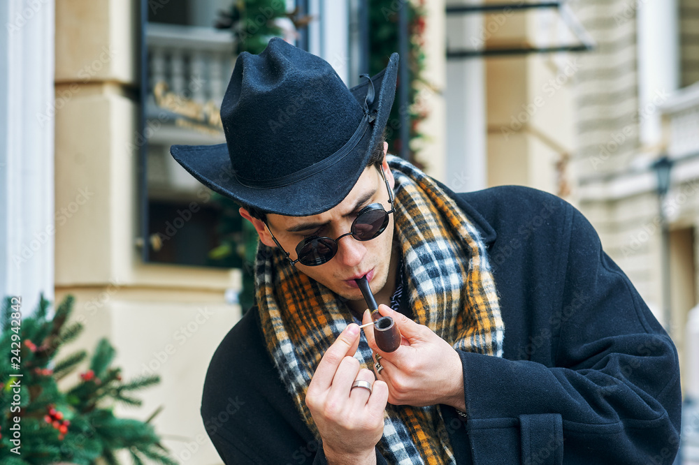 Portrait of a fashionable stylish man Smoking a pipe on a city street Portrait of a fashionable stylish man Smoking a pipe on a city street