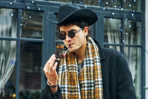 Portrait of a fashionable stylish man Smoking a pipe on a city street
