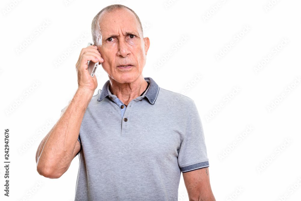 Studio shot of angry senior man talking on mobile phone Studio shot of angry senior man talking on mobile phone