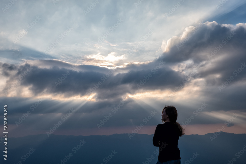 A beautiful asian woman standing and watching sunset with mountains view in the evening
