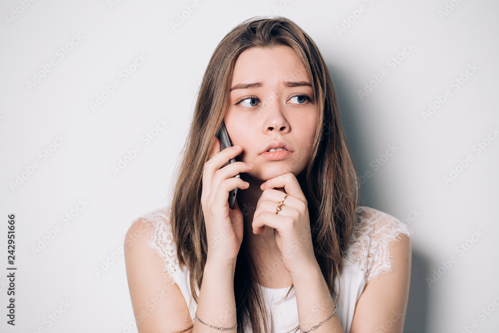 Frustrated annoyed sad woman with mobile phone. Young upset woman talking on phone in office. Unhappy, sad girl Frustrated annoyed sad woman with mobile phone. Young upset woman talking on phone in office. Unhappy, sad girl