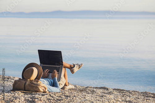 Bilde på lerret Young woman using laptop computer on a beach