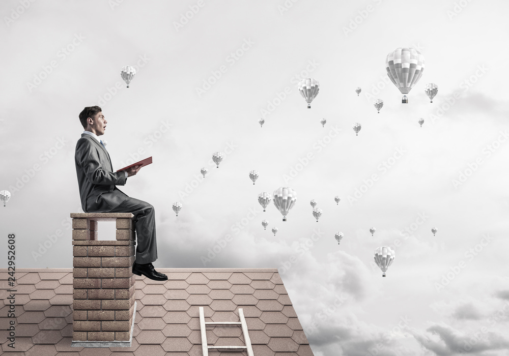 Man on roof reading book and aerostats flying in air Man on roof reading book and aerostats flying in air
