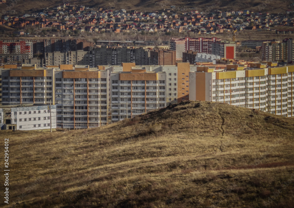 Residential area on the outskirts. Ust-Kamenogorsk (Kazakhstan). Hills. Multistory apartment buildings and cottages. Autumn landscape. Grunge. Hills