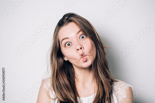 Close up indoor portrait of cool pretty young brunette girl. woman fooling around, making crazy funny grimace.