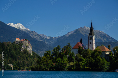 Iconic landscape view of beautiful St. Marys Church of Assumption on small island,lake Bled in Slovenia .Bled Castle on background. Summer scene travel Slovenia concept. Tourist popular attraction