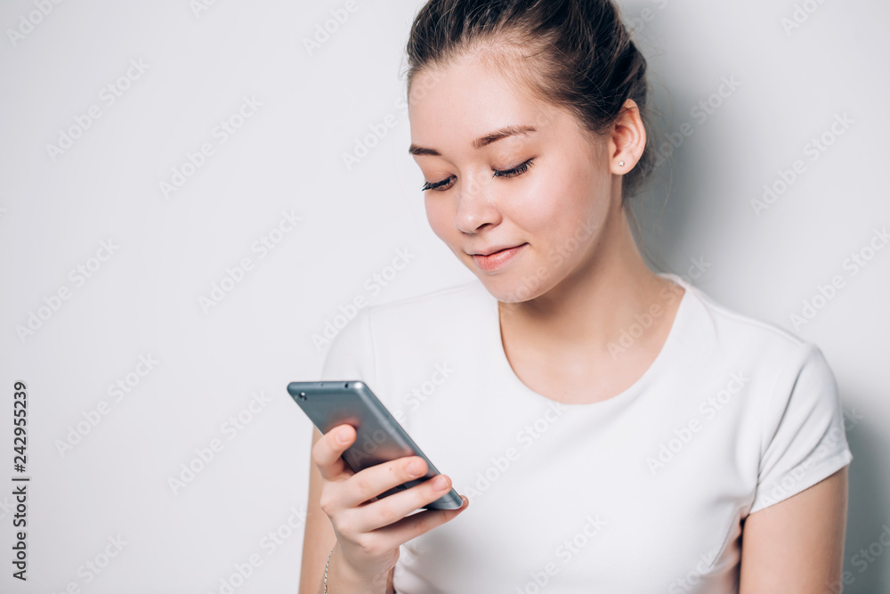Woman typing text message on smart phone. Beautiful girl on white background, close-up Woman typing text message on smart phone. Beautiful girl on white background, close-up
