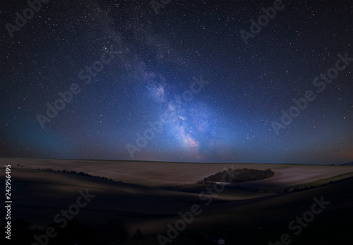 Vibrant Milky Way composite image over landscape of countryside of rolling hills and valleys