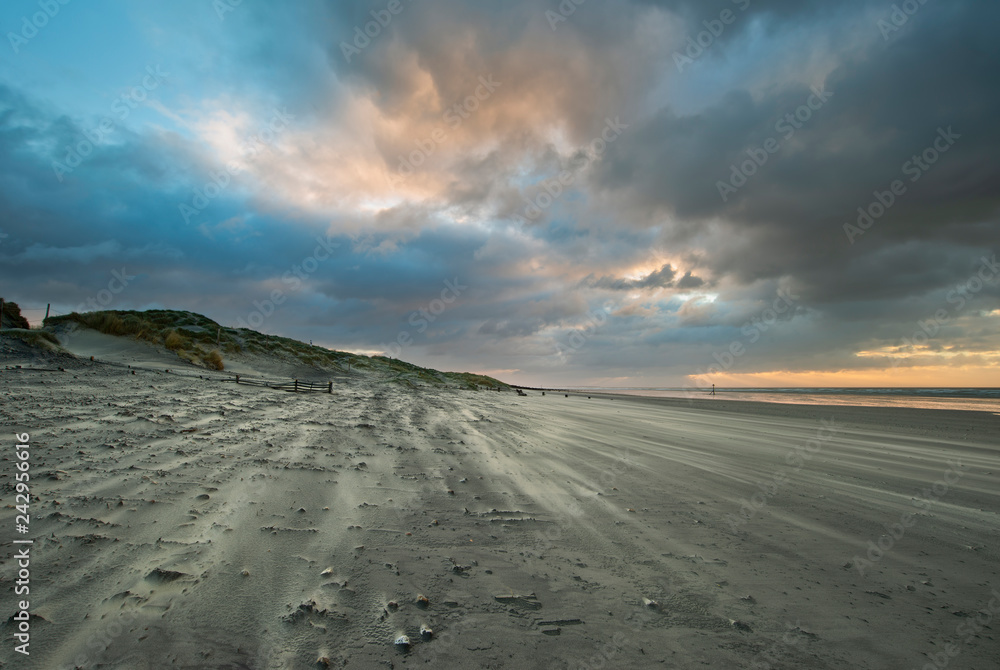 Stunning Winter sunrise over West Wittering beach in Sussex England with wind blowing sand across the beach
