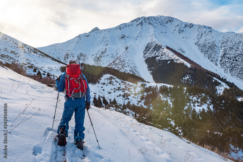 A man in the mountains. Ski touring on a split snowboard. A man stands with his back to the viewer and looks at the mountain landscape. Winter sport. A man in the mountains. Ski touring on a split snowboard. A man stands with his back to the viewer and looks at the mountain landscape. Winter sport.