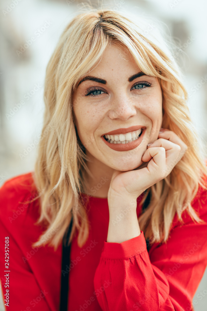 Fototapeta premium Smiling blonde girl with red shirt enjoying life outdoors.