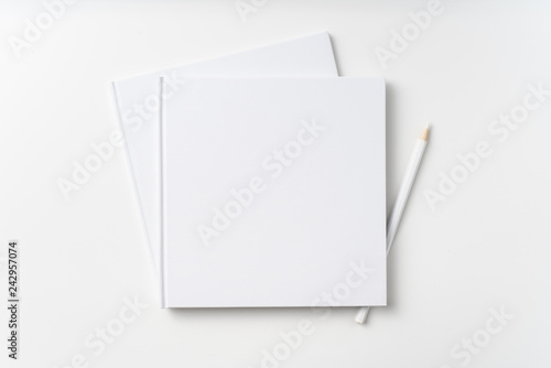 Top view of 2 white hardcover notebook, pencil