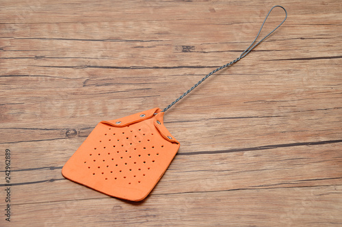 A fly swatter on a wooden background photo