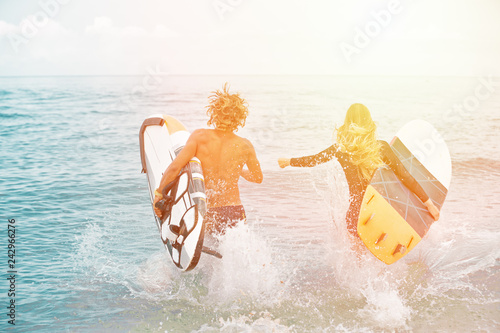 Photography Surfers at the beach- Smiling couple of surfers walking on the beach and having fun in summer