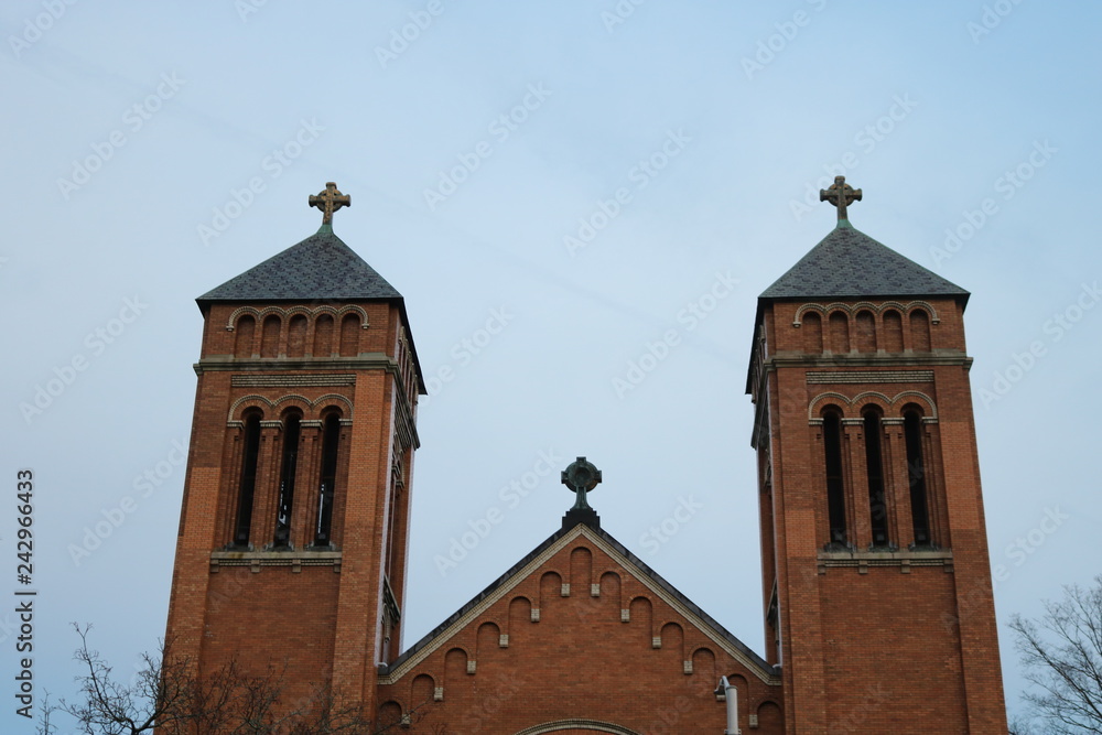 Old historic stone Catholic church steeple against bright blue skies