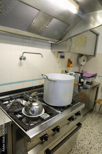 industrial kitchen with a metal pot on the stove and a teapot