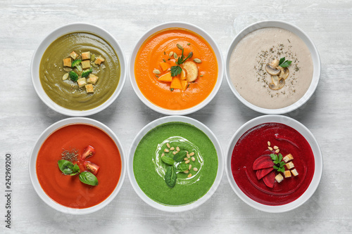 Various soups in bowls on wooden background, top view. Healthy food