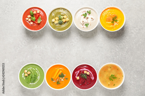 Various cream soups in bowls and space for text on grey background, top view