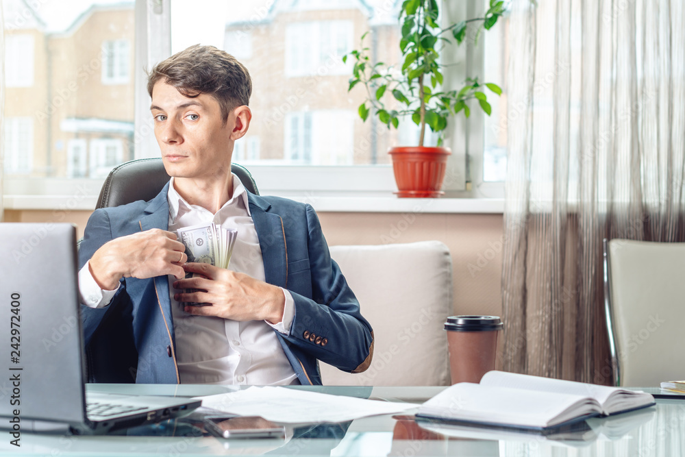 Businessman official sitting in the office hides a bribe unnoticed in his pocket. Corruption and bribery Businessman official sitting in the office hides a bribe unnoticed in his pocket. Corruption and bribery