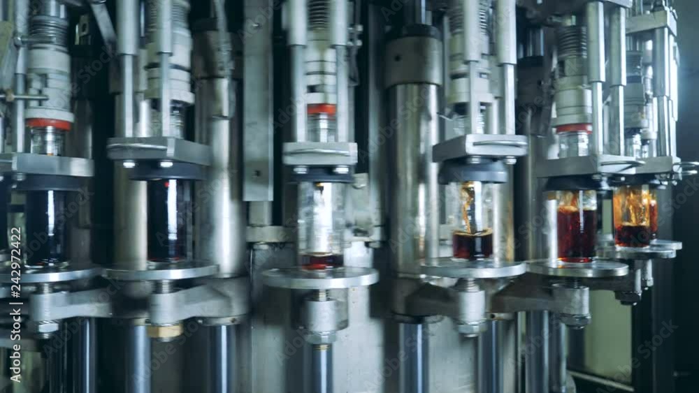 Rotating industrial machine filling glass bottles with beverage Rotating industrial machine filling glass bottles with beverage