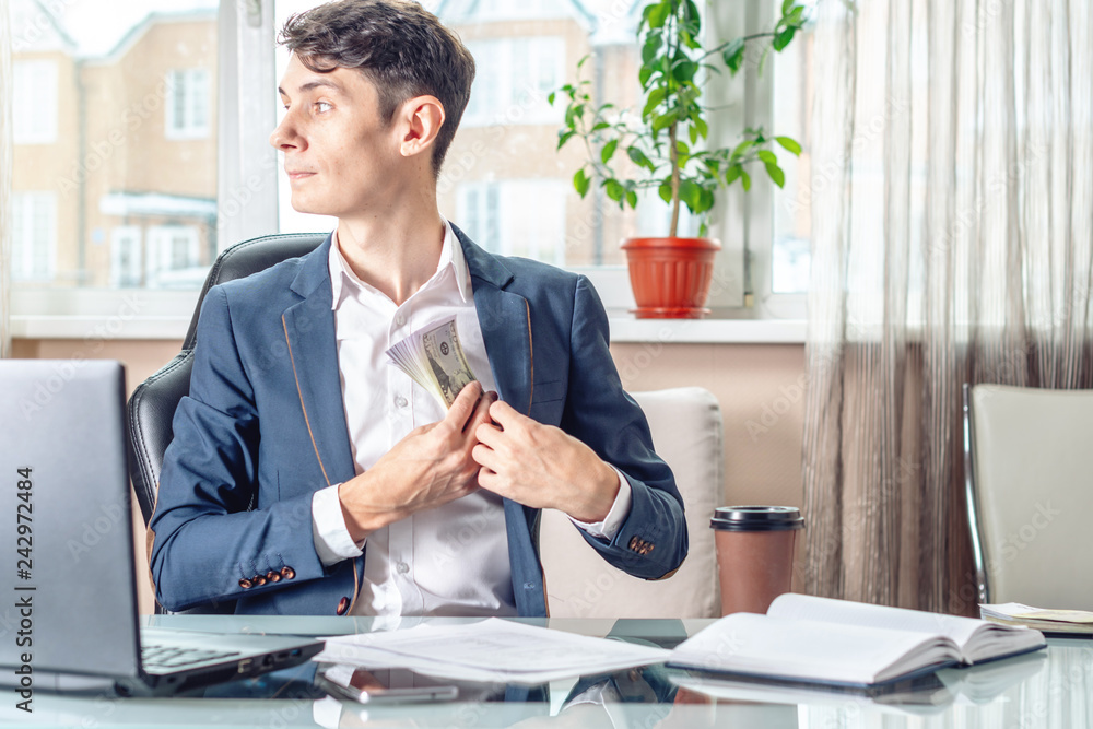 Businessman official sitting in the office hides a bribe unnoticed in his pocket. Corruption and bribery Businessman official sitting in the office hides a bribe unnoticed in his pocket. Corruption and bribery