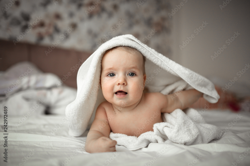 baby in towel is lying on his stomach on bed baby in towel is lying on his stomach on bed