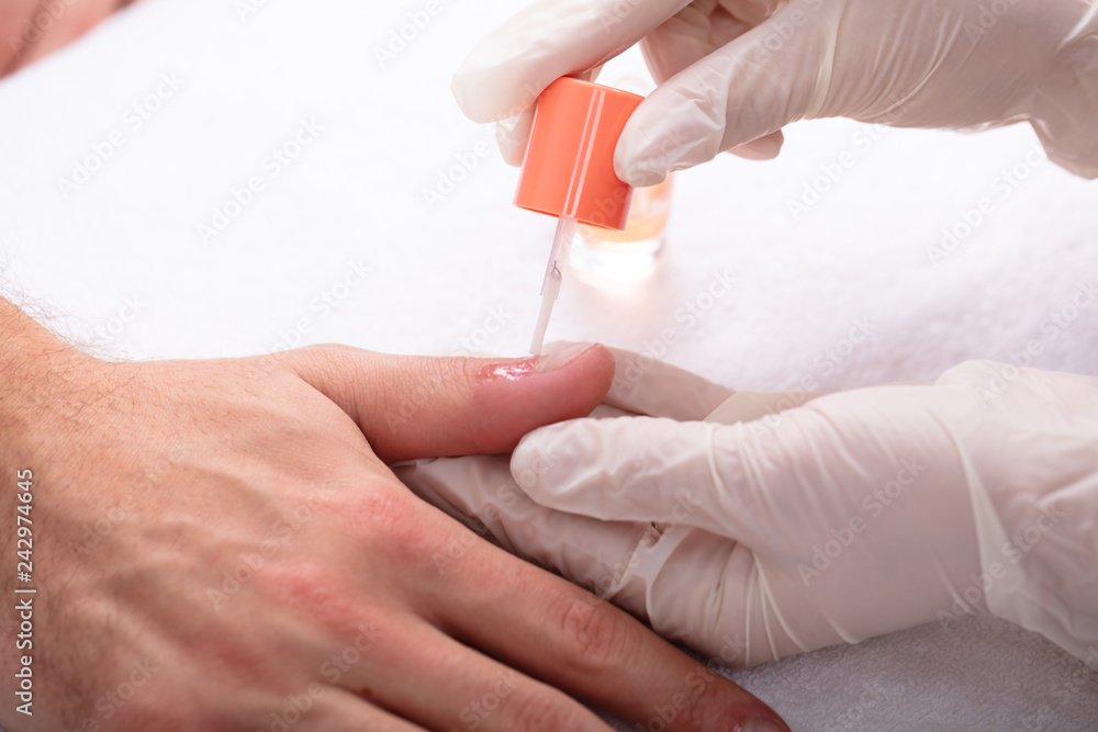Beautician Applying Nail Oil On Man's Hand Beautician Applying Nail Oil On Man's Hand