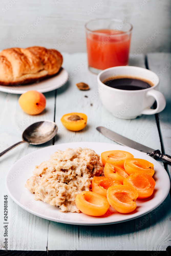 Porridge with apricot, coffee, glass of juice and croissant Porridge with apricot, coffee, glass of juice and croissant