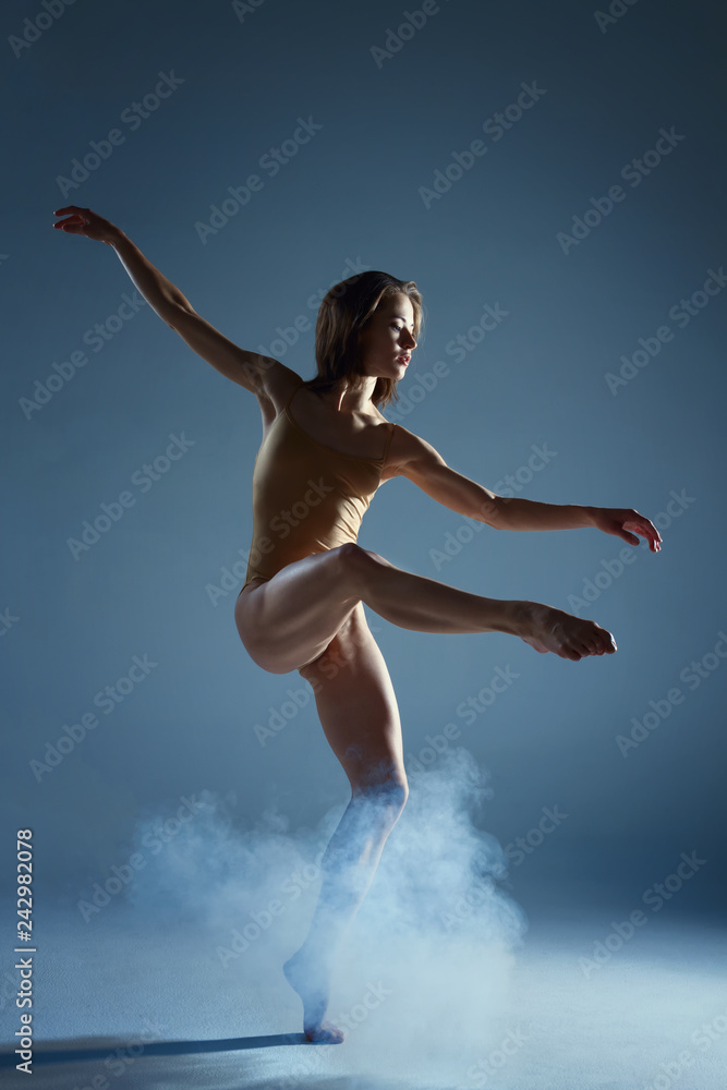 Naklejka premium Dancing in cloud concept. Muscle brunette beauty female girl adult woman dancer athlete in fog smoke fume wearing dance bodysuit making emotional dance element performance on isolated grey background