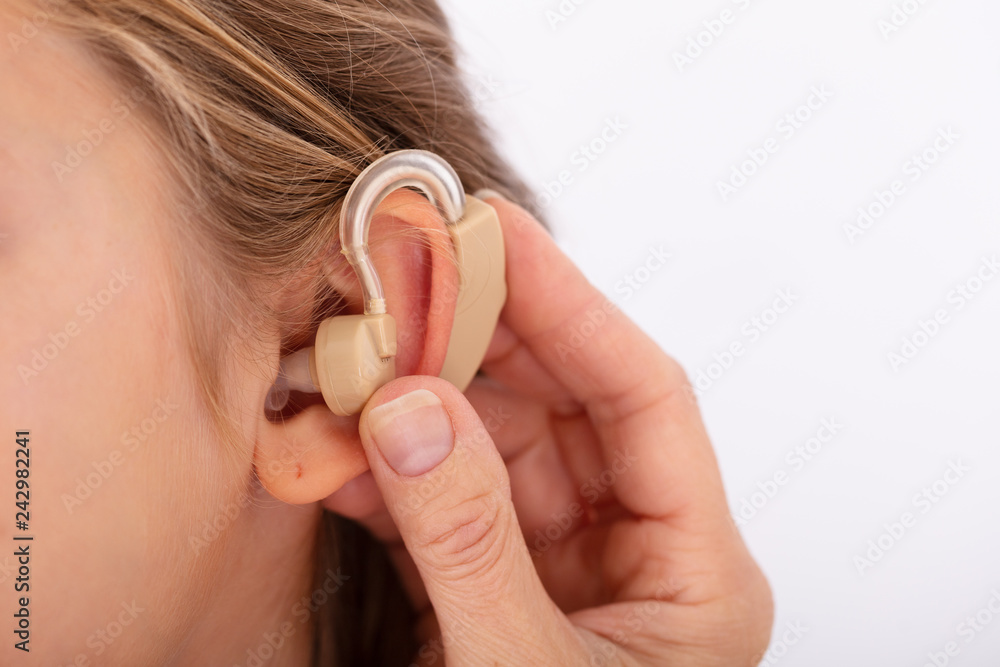 Fototapeta premium Doctor Inserting Hearing Aid In Girl's Ear