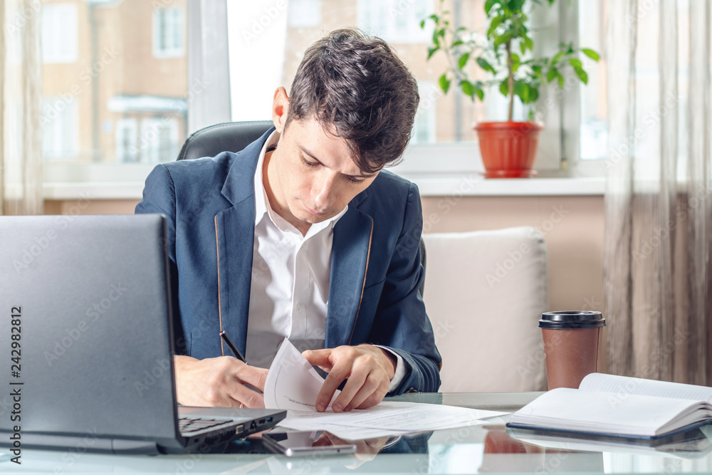 Businessman sitting at the table signing documents in the office. Transactions and work with securities