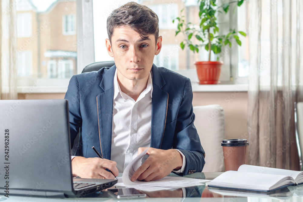 Fototapeta premium Businessman sitting at the table signing documents in the office. Transactions and work with securities