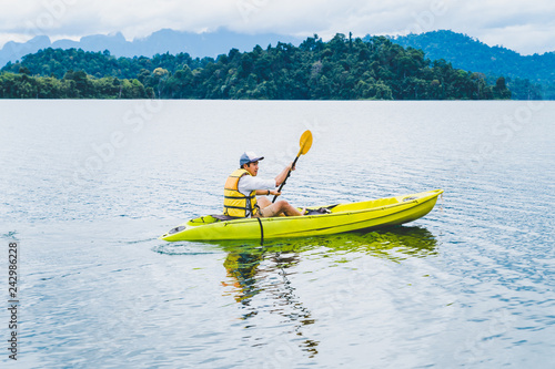 Sport and recreations. Young man enjoy vacations with kayak in Cheow Lan Lake or Rajjaprabha Dam Reservoir, Surat Thani, Thailand.