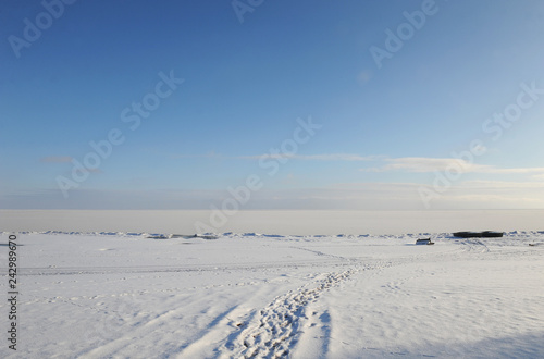 Winter snowy coastal landscape on a sunny day. Frozen river. Clear sky. Open space. Two boats on the shore