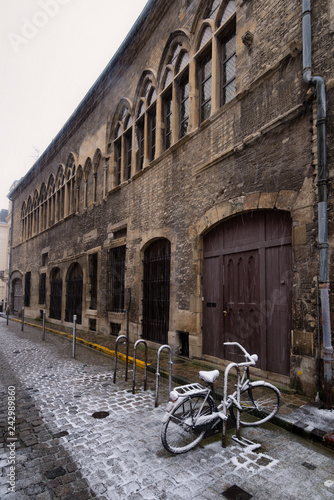 One lost street with historic building and bicycle undre the snow in Reims, France