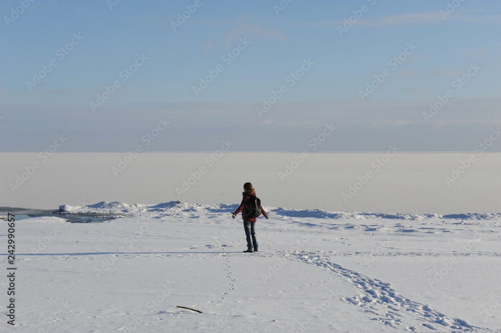 Winter snowy coastal landscape on a sunny day. Frozen river. Clear sky. Open space. The figure of single traveler