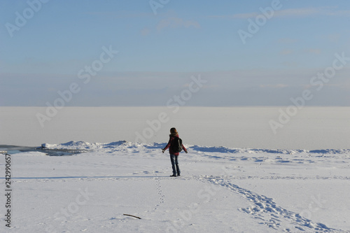 Winter snowy coastal landscape on a sunny day. Frozen river. Clear sky. Open space. The figure of single traveler