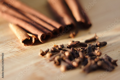 fragrant spices: cinnamon sticks and cloves lie on a wooden Board, lit by the pleasant sun photo
