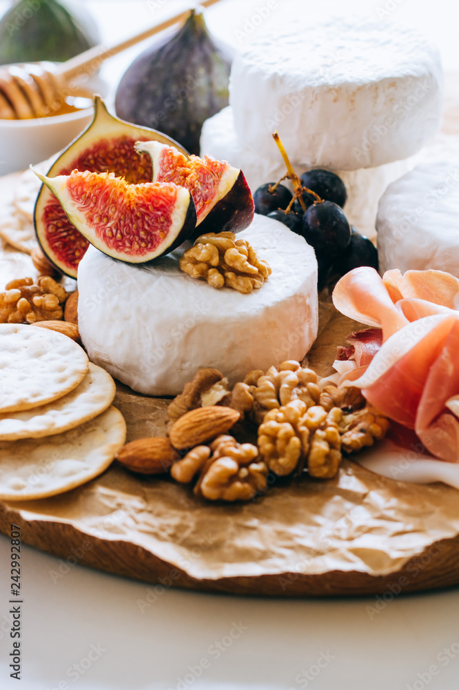Camembert cheese, figs, jamon, honey and grapes. Cheese plate on marble background Camembert cheese, figs, jamon, honey and grapes. Cheese plate on marble background