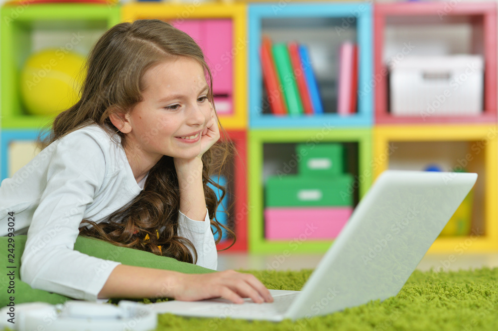 Emotional cute girl using laptop while lying on green floor Emotional cute girl using laptop while lying on green floor