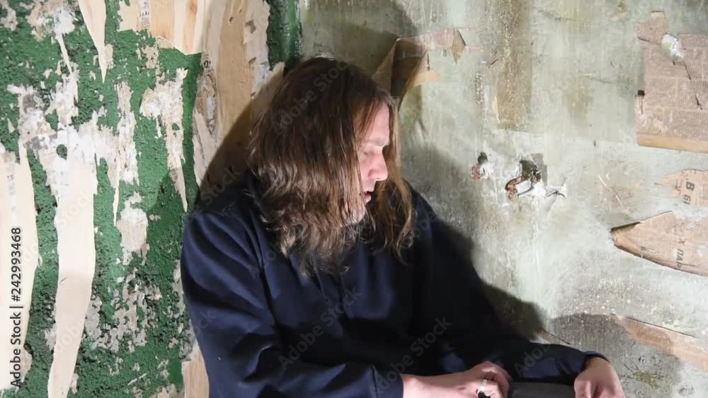 Depressed and angry man is sitting in the corner in an abandoned house Depressed and angry man is sitting in the corner in an abandoned house