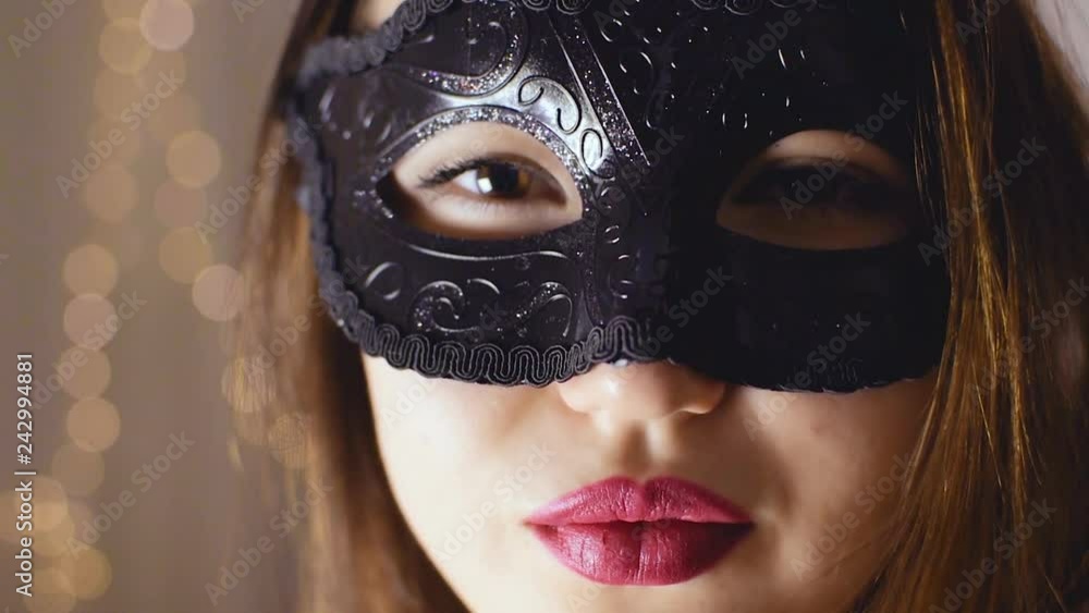 A brown-haired girl in a black mask looks into the camera A brown-haired girl in a black mask looks into the camera