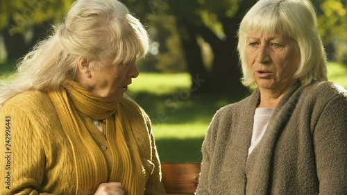 Elderly woman whispering rumor to friend, scandalous news shocks pensioners photo