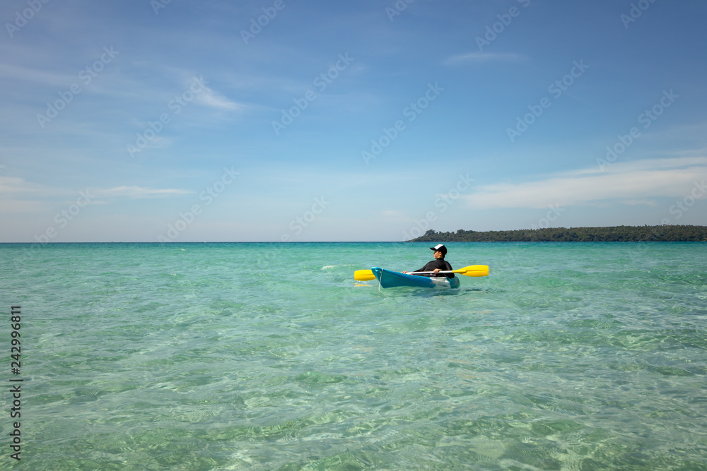 Asian boy in swimsuit rowing kayak at sea on sunshine day