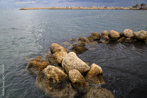 Kamienny krąg w morzu, na horyzoncie skalisty falochron w porcie, Larnaca, Cypr