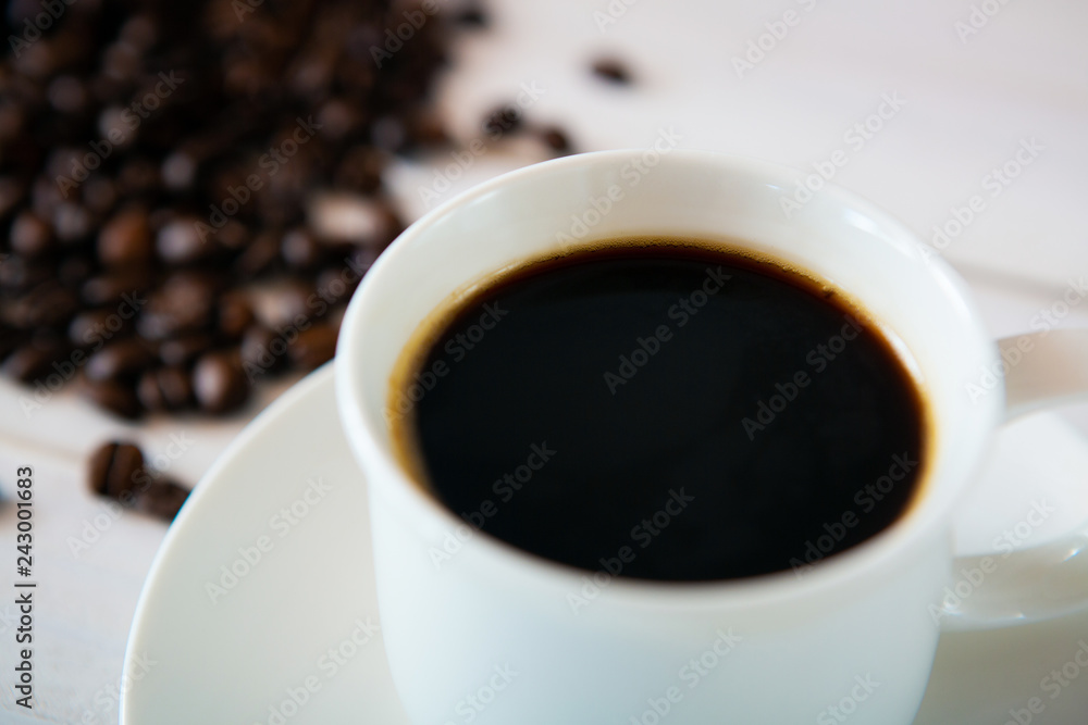 Fototapeta premium cup of coffee and beans on white wooden background