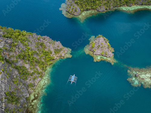 Aerial view to tropical lagoon with azure water and traditional sailing boat near Kayangan Lake, Coron island. Palawan, Philippines.