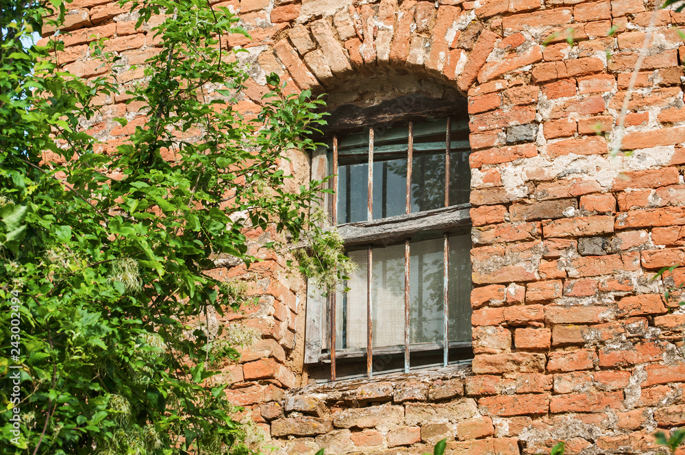 Grunge broken  window of old rural weathered neglected abandoned house red brick wall closeup